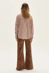 Camisa de manga larga con cuello y puños, confeccionada en tejido de rayas verticales en tonos crema y bordó. Presenta un bolsillo de parche en el pecho con un bordado exclusivo.