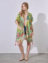 Kimono tejido con estampado de hojas y flores en tonos verdes, amarillos y rosados. Tiene mangas japonesas y terminación con borlas rosadas.