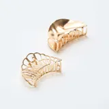 Set de dos pinzas para el pelo de metal dorado con diseño de concha marina, una con acabado liso y otra con estructura calada.
