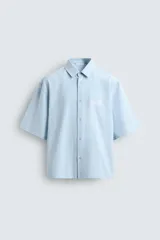 Camisa de corte relajado confeccionada en tejido de mezcla de algodón, con estampado de rayas verticales en tonos azul y blanco. Presenta cuello solapa, manga corta y cierre frontal con botones. Incluye un detalle bordado a contraste en el pecho.