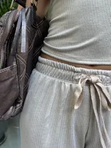 Pantalón de mujer color beige, de tela morley elastizada con líneas finas, corte holgado, cintura elástica con cordón ajustable y bolsillos funcionales.