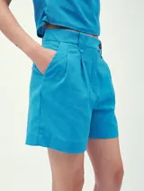 Short de vestir celeste con pinzas delanteras y cierre con botón.