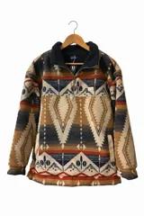 Buzo de polar con diseño estampado de estilo azteca en tonos tierra, azul y naranja. Presenta cuello alto con cierre frontal parcial, mangas largas y bolsillos laterales.