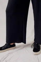 Pantalón negro de corte ancho, tiro alto y textura suave.