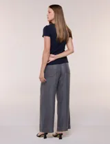 Remera básica de corte al cuerpo con textura acanalada, cuello redondo y mangas cortas. Presenta una pequeña placa metálica decorativa en el borde inferior.