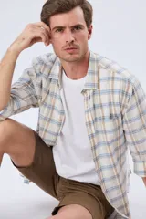 Camisa de manga larga de lino y algodón, con estampado a cuadros en tonos beige, blanco y celeste, cuello camisero y cierre frontal con botones.
