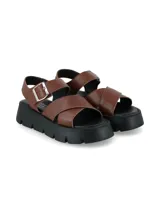 Sandalia de cuero graneado color marrón chocolate, con tiras cruzadas en el empeine, tira trasera con hebilla metálica de ajuste y suela de plataforma negra con diseño track.