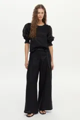 Blusa de lino blanca con escote redondo y mangas cortas abullonadas con detalles de volados en los puños.