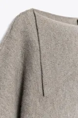 Jersey de punto de corte holgado con cuello solapa asimétrico y mangas anchas por debajo del codo.