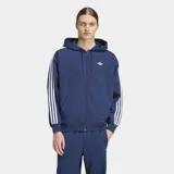 Campera con capucha Adidas Adicolor de corte holgado, color azul con cierre frontal de cremallera. Presenta las icónicas tres rayas blancas en las mangas y el logo del trébol bordado en el pecho.