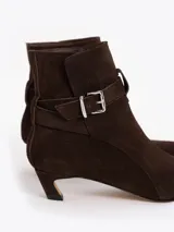 Bota de caña media confeccionada en cuero descarne, con punta fina, taco bajo forrado y detalle de tira con hebilla metálica en el tobillo.