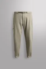 Pantalón de hombre color beige/caqui, de corte regular fit, confeccionado en tejido técnico compacto con elasticidad. Presenta cintura ajustable con cinturón a contraste, bolsillos frontales, bolsillo trasero con cierre de cremallera oculta y bolsillo cargo con cierre de cremallera oculta en la pernera.