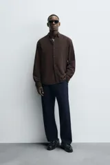 Camisa de corte regular fit confeccionada en tejido de algodón con textura de cuadrillé. Presenta cuello solapa, manga larga con puños abotonados y cierre frontal mediante botonadura.