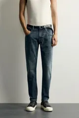 Jeans skinny fit de color azul, con efecto lavado y detalles de roturas en las piernas. Diseño de cinco bolsillos, tiro medio y cierre frontal con cremallera y botón.