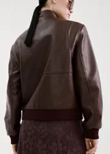 Chaqueta tipo bomber de cuero sintético color bordó, con cierre frontal, cuello alto y bolsillos delanteros amplios. Cuenta con puños y cintura de canalé elástico.