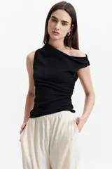 Remera negra de un hombro con corte asimétrico y frunces laterales.