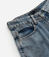 Bermuda baggy de jean color negro con pespuntes contrastantes, cierre de botón y cremallera, y bolsillos.