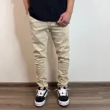 Jean de corte skinny color beige, con diseño de cinco bolsillos y cierre frontal con botón y cremallera.