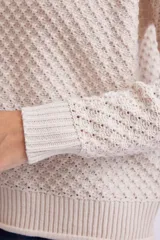 Buzo de tejido de punto con textura en color crudo, de corte holgado, cuello redondo y puños y ruedo acanalados.