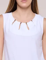 Blusa blanca de seda fría, sin mangas, con escote redondo, frunces sutiles y pequeñas aberturas verticales sujetas por cuentas metálicas doradas.