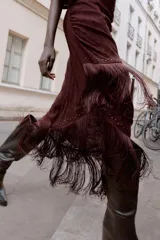 Vestido midi asimétrico de un solo hombro en color bordó, confeccionado en tejido devoré con diseño floral y detalles de terciopelo. Presenta frunces laterales, bajo con flecos largos y aplicación de tachas metálicas. Incluye forro interior y cierre lateral con cremallera oculta.