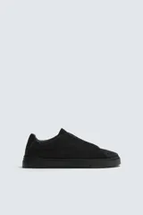 Zapatilla urbana de hombre con parte superior de piel con acabado en serraje color marrón. Presenta un diseño minimalista con cordonera oculta y suela de goma a contraste en color negro.