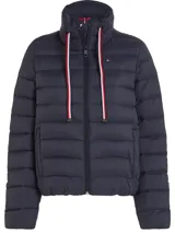 Campera acolchada azul marino con cuello alto, cierre frontal con cremallera y bolsillos laterales con ojal. Presenta detalles distintivos de la marca Tommy Hilfiger, como la cinta con los colores de la marca en el cierre y el logo bordado en el pecho.