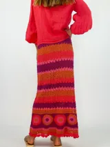 Pollera larga tejida a crochet con diseño de rayas horizontales en tonos naranja, fucsia y morado.