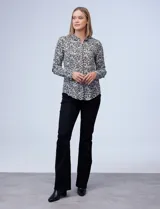 Camisa estampada blanca y negra con cuello clásico, abertura frontal con botones ocultos y mangas largas con puños abotonados.