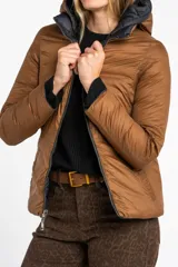 Campera reversible con diseño acolchado, cierre frontal y capucha. Un lado es de color negro y el otro de color tostado, con puños tejidos en color negro.
