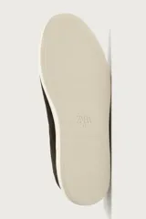Zapatilla urbana de hombre confeccionada en piel con acabado de serraje, diseño minimalista sin cordones visibles y suela de goma a contraste.
