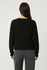 Sweater de tejido de punto liso, color blanco, con cuello redondo a la base, mangas largas y diseño holgado.