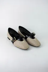 Guillerminas flat de ecocuero color beige con diseño calado en rombos y detalles en negro charol en la puntera y tira con hebilla dorada.