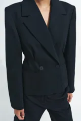 Blazer entallada de Zara, confeccionada en hilatura con lana. Presenta cuello solapa de muescas, manga larga con botones en puños, bolsillos de vivo en el delantero y cierre frontal cruzado con botones.