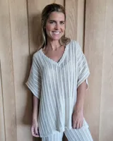 Remerón de tejido de punto calado en color arena, con cuello en V con terminación festoneada y mangas cortas amplias.