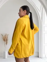 Blazer amarillo mostaza de crepe con solapas y bolsillos delanteros.