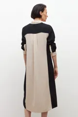 Vestido camisero midi de lino, color beige con paneles laterales en negro, cuello camisero, cierre frontal con botones y mangas largas con puños abotonados.