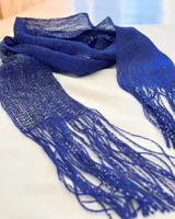 Corbatín de tejido abierto en color azul vibrante con hilos brillantes entrelazados, terminado en flecos largos en ambos extremos.