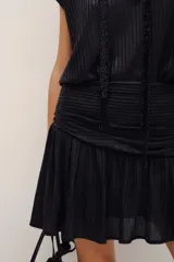 Falda corta de corte cruzado con volados en el borde inferior, confeccionada en tejido metalizado dorado.