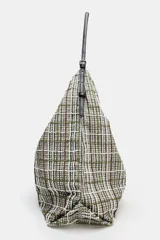 Bolso tipo shopper de tejido con diseño de cuadros en tonos verdes, blancos y marrones, decorado con apliques brillantes. Cuenta con asa de hombro ajustable en material sintético negro, cierre mediante botón imantado y bolsillo interior con cremallera.