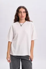 Remera manga corta texturada color crudo con parche bordado decorativo en la espalda.