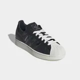 Championes Adidas Superstar II de color negro con la icónica puntera de caucho en relieve y suela blanca. Presenta detalles con estampado de piel de serpiente en las tres tiras laterales y en el talón, además de cordones blancos y el nombre del modelo en dorado.