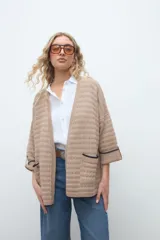 Kimono de tejido de punto en color beige, con diseño abierto al frente, mangas tres cuartos y bolsillos aplicados con ribete oscuro.