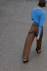 Jeans de tiro medio con diseño wide leg, confeccionados en denim color marrón con efecto lavado. Presentan cinco bolsillos, cierre frontal con cremallera y doble botón metálico.