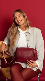 Bandolera de símil cuero color bordó, con apertura central con cierre, bolsillo principal con cierre metálico, y bolsillo frontal con tapa y broches magnéticos. Incluye bolsillos internos y posterior, y correa de galón combinada larga y regulable.