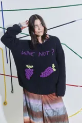 Sweater tejido de lana merino color negro, con bordado de uvas y texto 'Wine Not?'. De calce holgado, cuello a la base y puños.