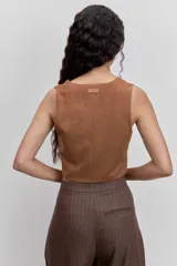 Chaleco corto marrón con estampado de rayas finas verticales, escote en V y cierre frontal con botones. Presenta detalles en los hombros y laterales en color tostado con efecto piel.