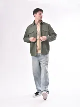 Campera verde militar con cuello clásico, cierre frontal con botones, dos bolsillos con solapa en el pecho y corte recto.