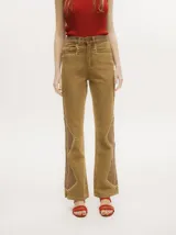 Pantalón de jean estilo oxford y tiro alto, color tostado, con apliques metalizados en forma de tachas que bordean los laterales y costuras.