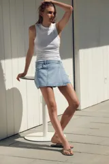 Falda pantalón corta de tiro alto confeccionada en denim celeste. Presenta bolsillos delanteros y traseros. Cierre frontal cruzado con cremallera oculta y botón metálico.